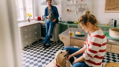 A couple with their healthy and happy dog in the kitchen.
